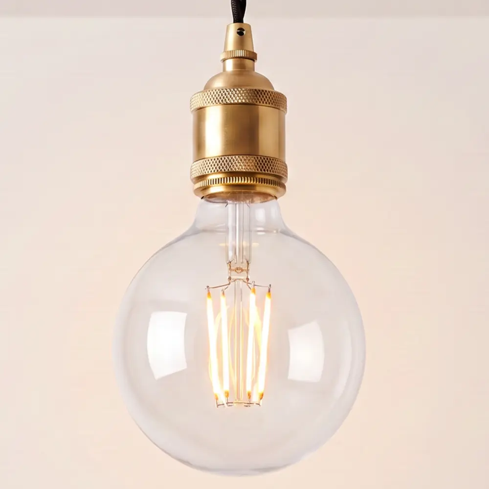 Close detail of the knurled brass bulb holder and clear globe filament bulb