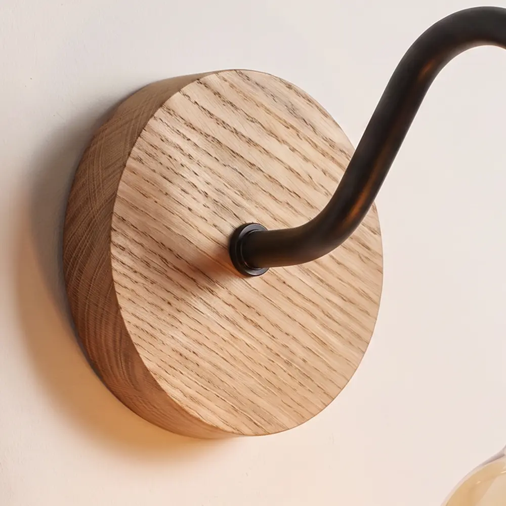 Close detail of the turned natural oak back plate and the black collar where the swan neck arm meets it
