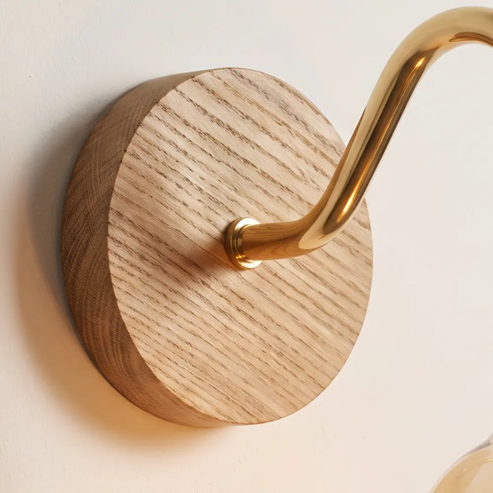 Close detail of the turned natural oak back plate and the brass collar where the swan neck arm meets it