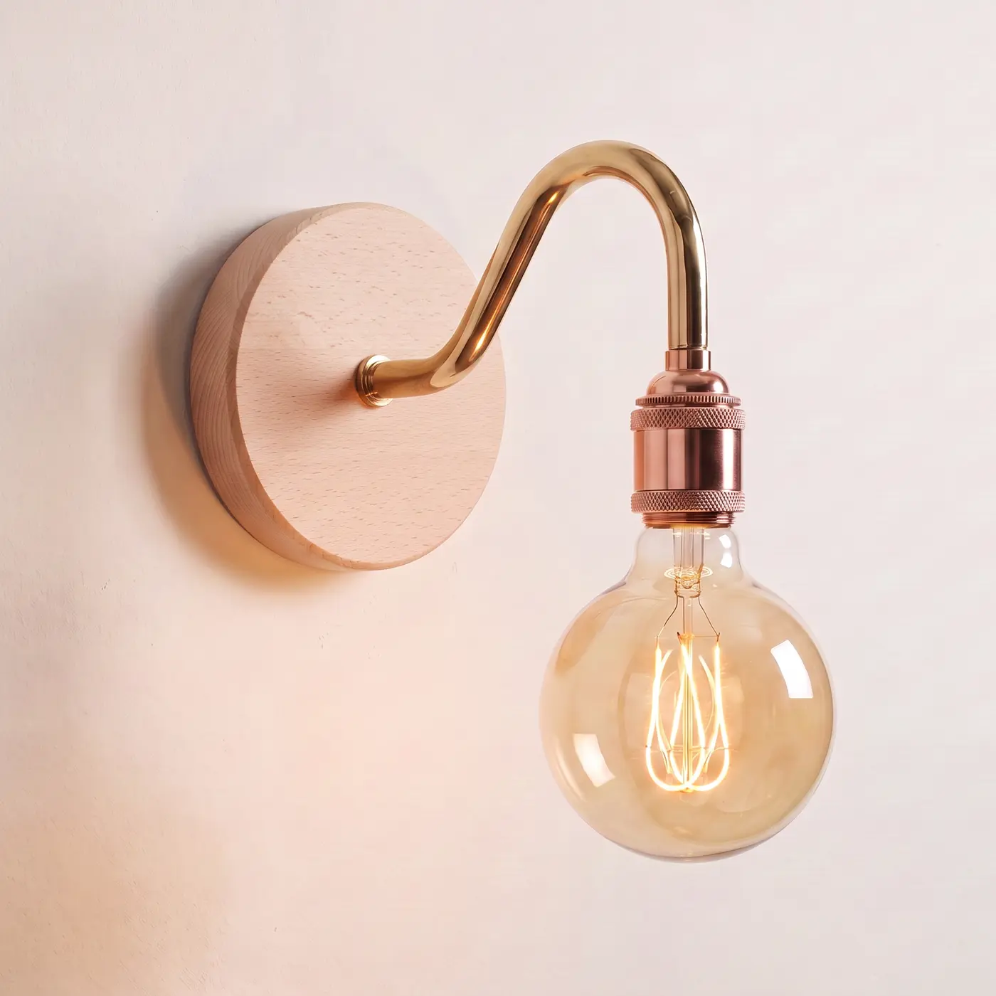 Swan neck wall light with a beech back plate, brass swan neck arm and copper bulb holder, lit with a globe filament bulb